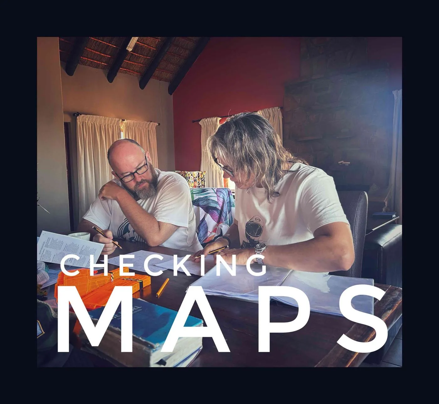 A man and a woman leaning over maps on a table, captioned Checking maps.